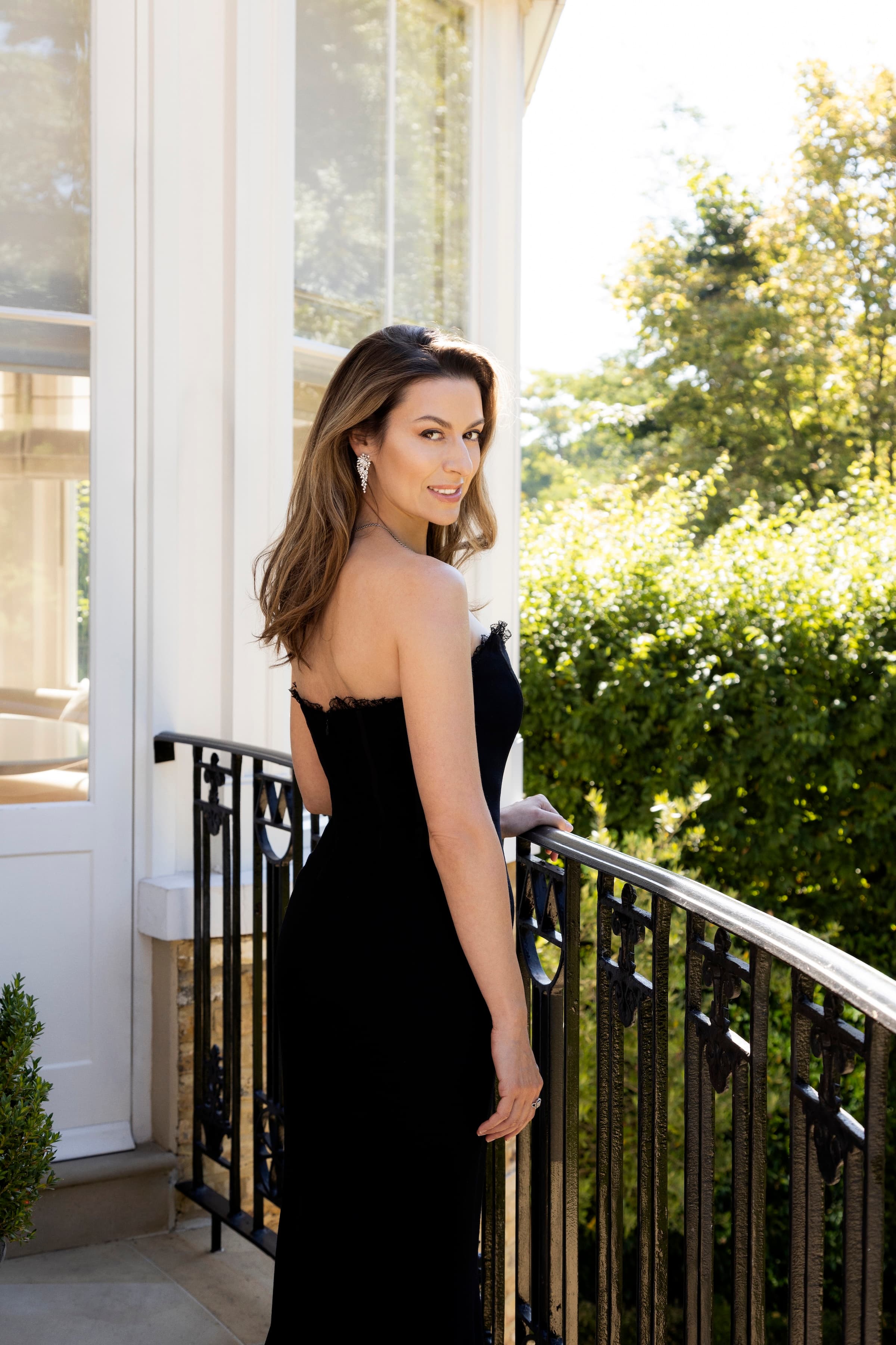 Chen Reiss in a black gown on a balcony in golden afternoon light